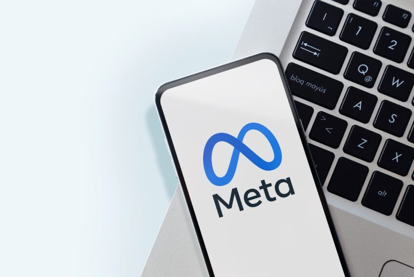 A-smartphone-displaying-the-Meta-logo-rests-on-a-laptop-keyboard-with-a-light-background
