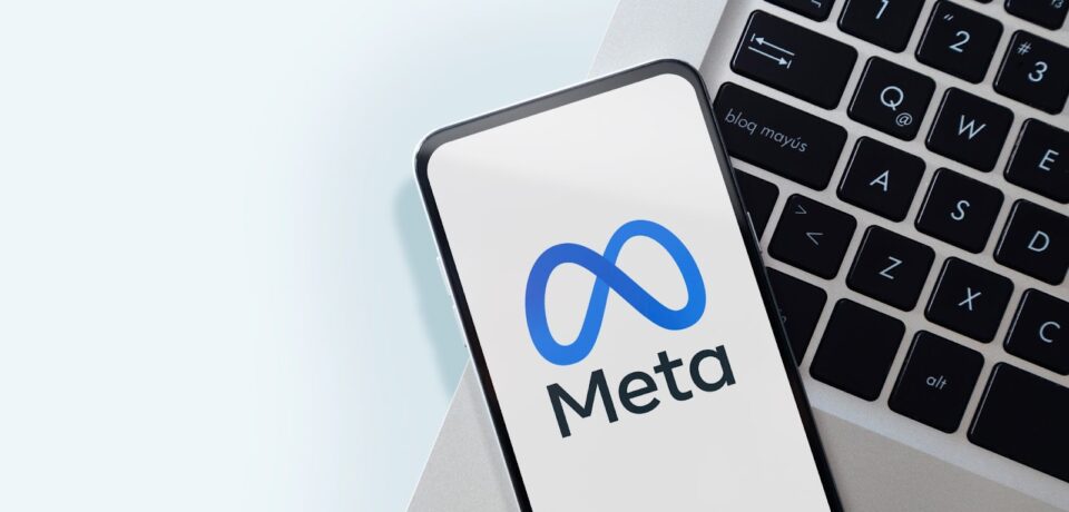A-smartphone-displaying-the-Meta-logo-rests-on-a-laptop-keyboard-with-a-light-background
