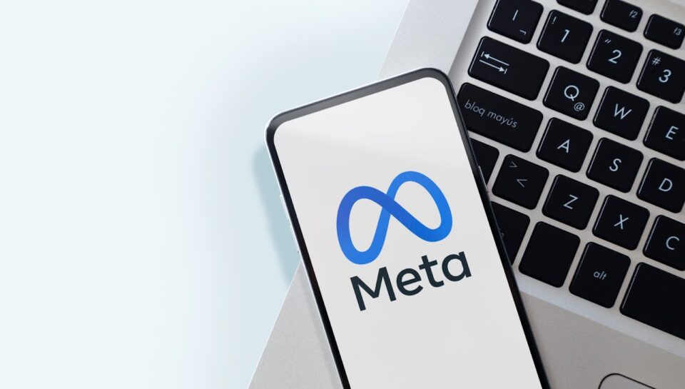 A-smartphone-displaying-the-Meta-logo-rests-on-a-laptop-keyboard-with-a-light-background